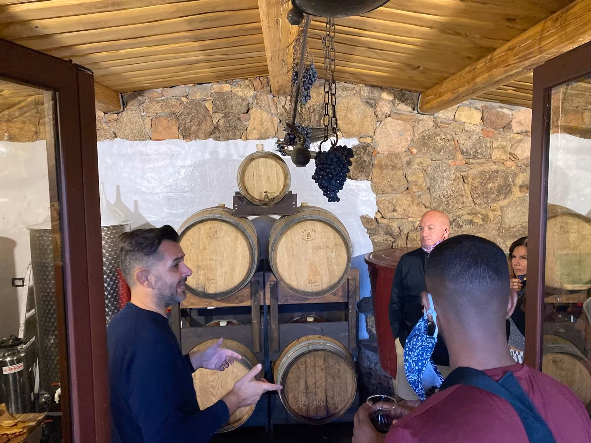 Guests enjoy wine tasting in a rustic Sardinian cellar during a pasta workshop tour in Olbia's ancient village.