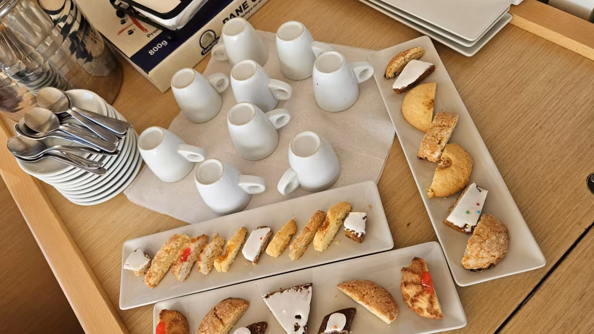 Assorted Sardinian pastries and coffee cups arranged on a wooden table aboard the La Maddalena catamaran tour.
