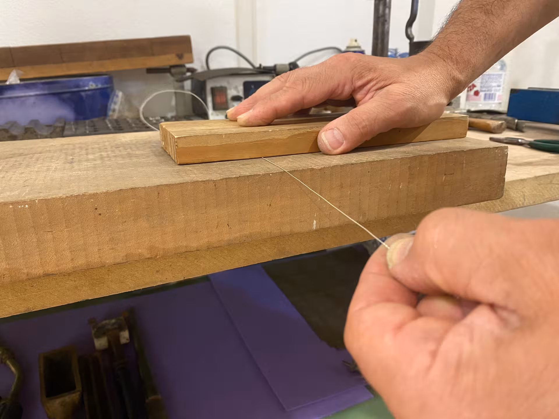 Hands crafting delicate wire at a filigree goldsmith workshop in Sassari, showcasing traditional jewelry techniques.