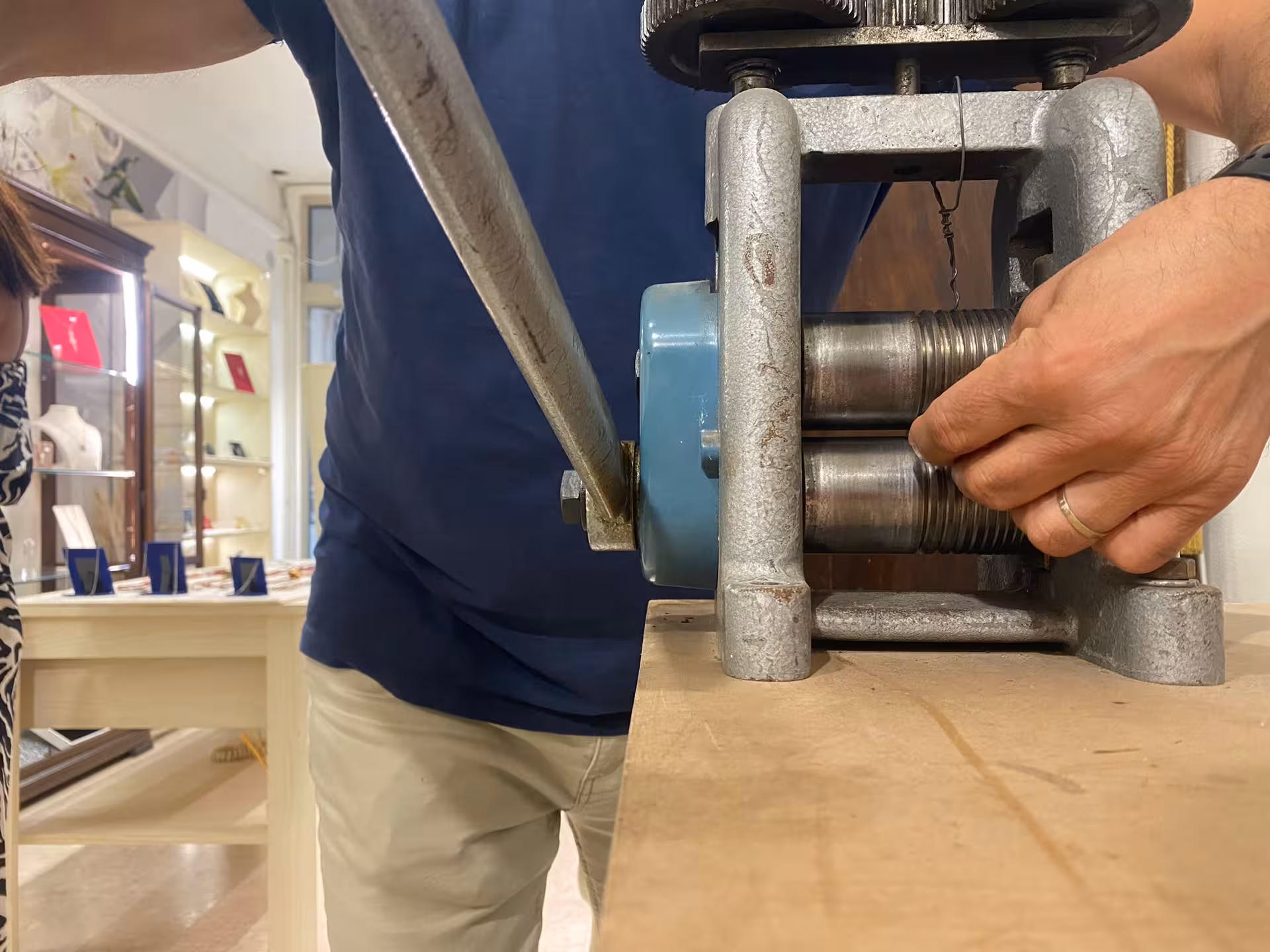 Expert operating a rolling mill at a Sassari goldsmith workshop, highlighting traditional filigree jewelry crafting.
