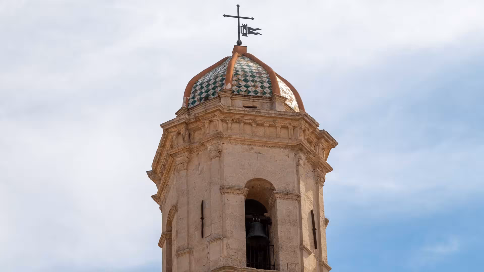Close-up of a historic bell tower with patterned dome in Sassari's historic center, perfect for cultural tours.