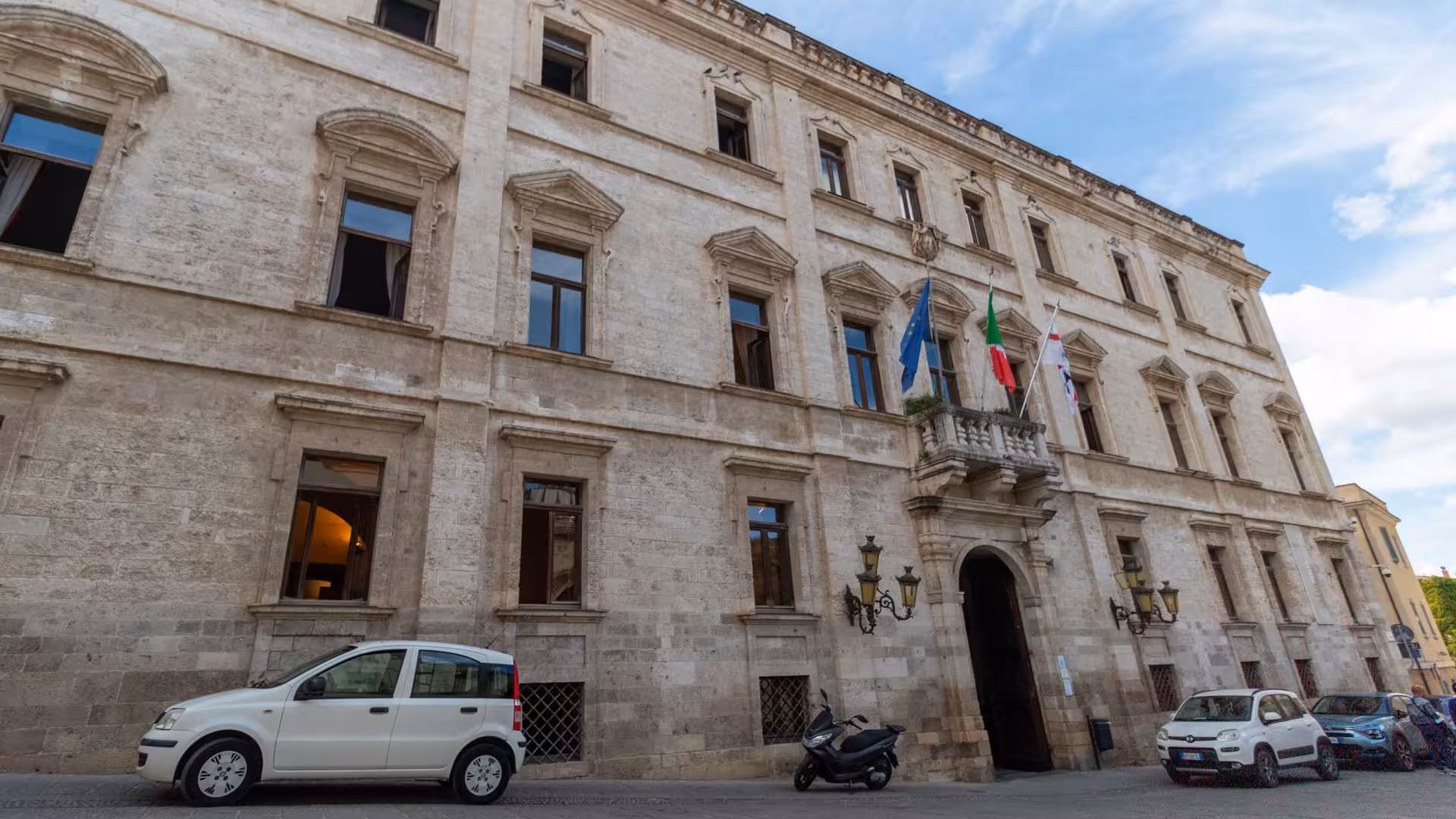 Elegant facade of a historic Sassari building with flags, a key highlight on the historic center walking tour.