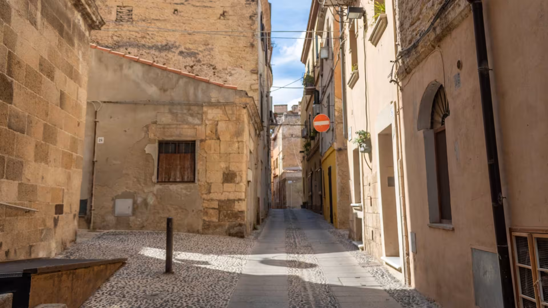 Narrow cobblestone street lined with ancient buildings in the heart of Sassari's historic center.