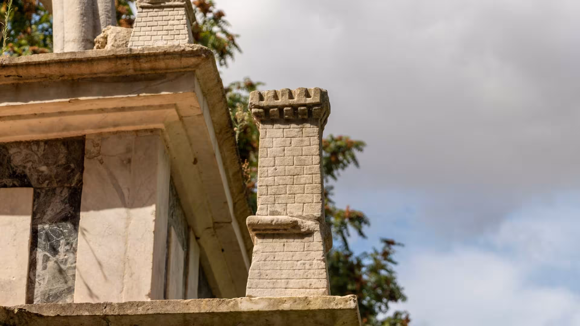 Close-up of ancient architectural details in Sassari's historic center, featuring intricate stone carvings and cloudy sky.