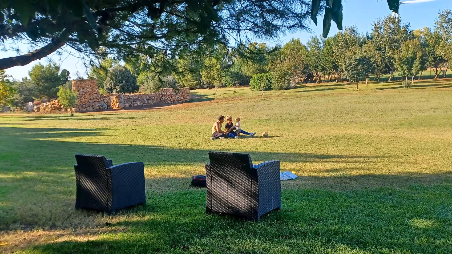 Family enjoying a sunny day on the grassy fields of Sassari's Roman Castrum educational farm.