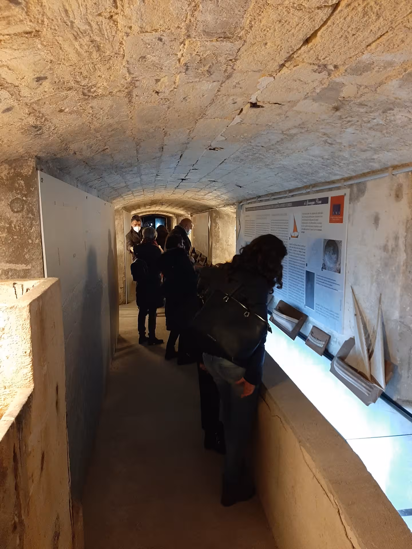 Tourists explore informative displays in a narrow passage of Sassari's Sea and Water Ecomuseum.