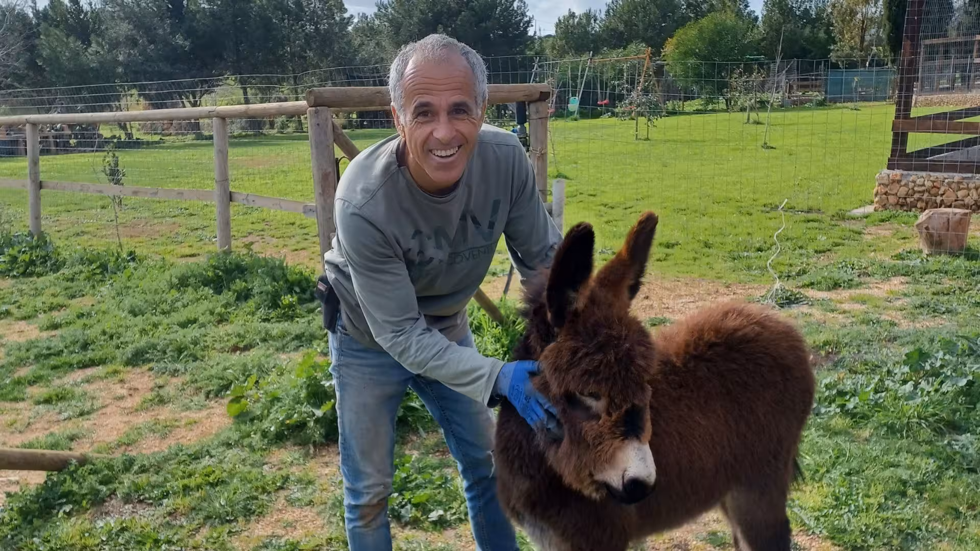 Smiling visitor interacting with a friendly donkey at Sassari's educational farm, ideal for family-friendly tours.