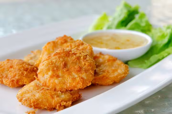 Crispy golden Scandinavian fish cakes with dipping sauce and lettuce, featured on Copenhagen Food & Drink Private Tour.