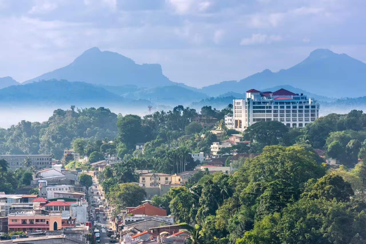 Scenic view of a hill town with lush greenery and distant mountains, ideal for a private tour in a serene setting.