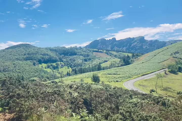Panoramic view of lush green mountains under a clear blue sky, perfect for scenic hikes and nature exploration.