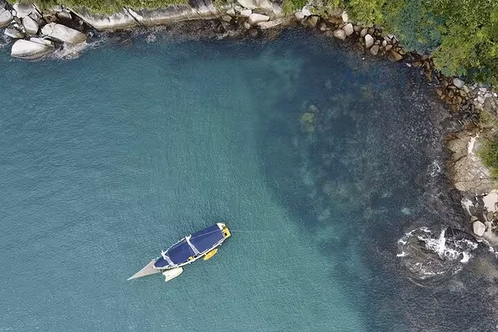 Schooner floating in clear turquoise waters near a rocky shoreline, perfect for standup paddle and kayak adventures.