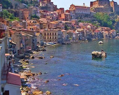 Colorful seaside houses and medieval fortress of Scilla, Calabria, overlooking rocky Tyrrhenian coast on guided Italy tour