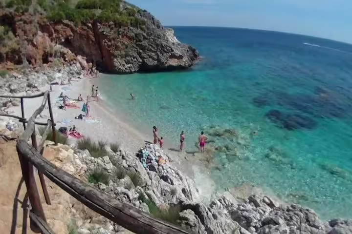 Swimmers enjoy crystal-clear water at a hidden cove in Scopello on a private Palermo coastal tour in western Sicily