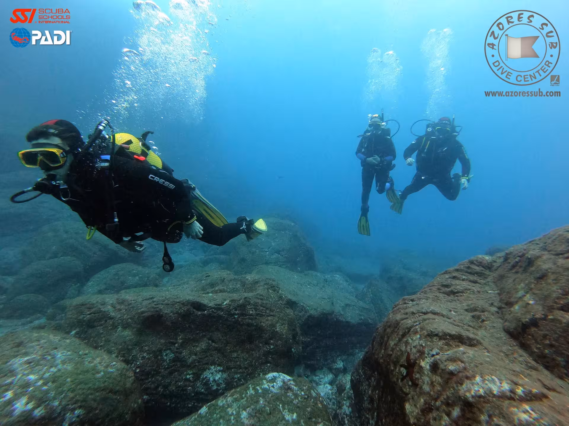 Guided scuba dive in the Azores with three divers over volcanic rocks, ideal for PADI beginners and certified dives
