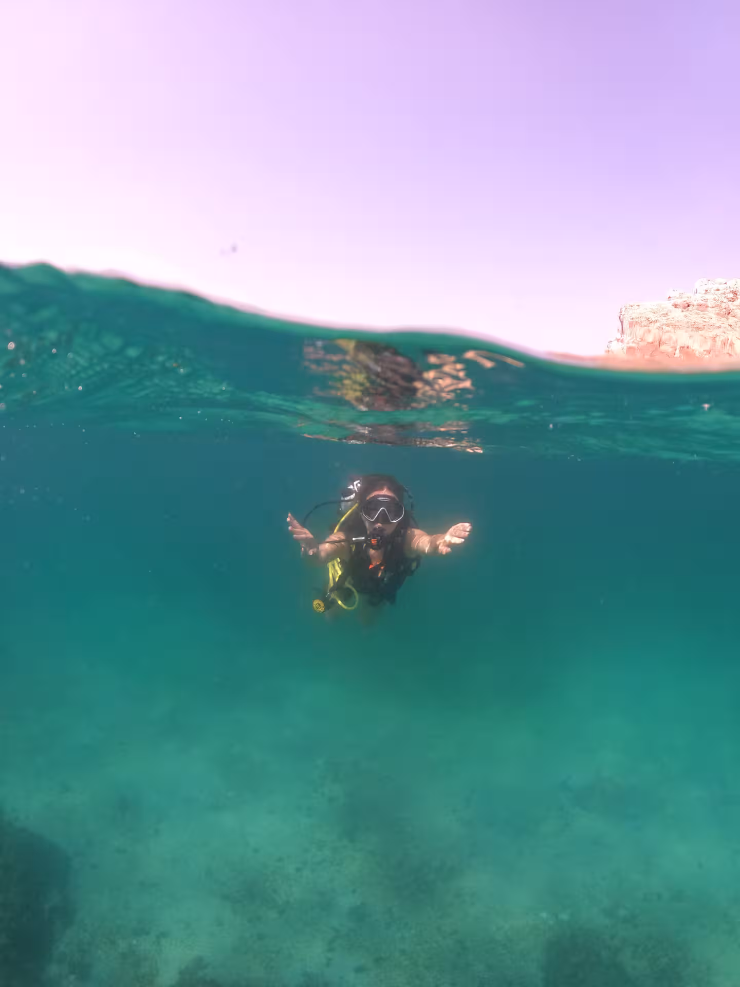 Scuba diver ascending towards the surface in Fujairah's vibrant waters, part of the Dubai to Fujairah diving tour.