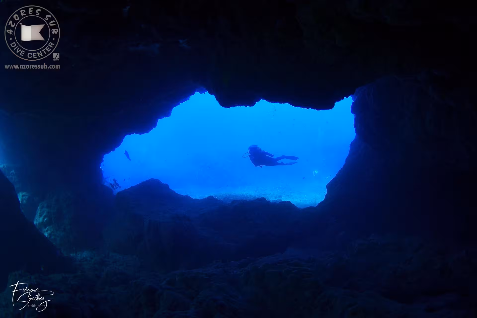 Scuba diver silhouetted in a blue ocean cave exit, a highlight of the Diving Exit tour in the Azores