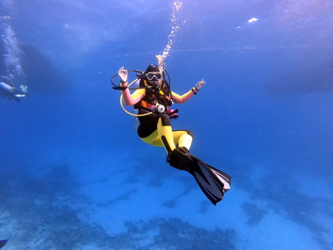 Scuba diver in clear Red Sea water on Orange Bay Island tour from Hurghada, Egypt, underwater adventure