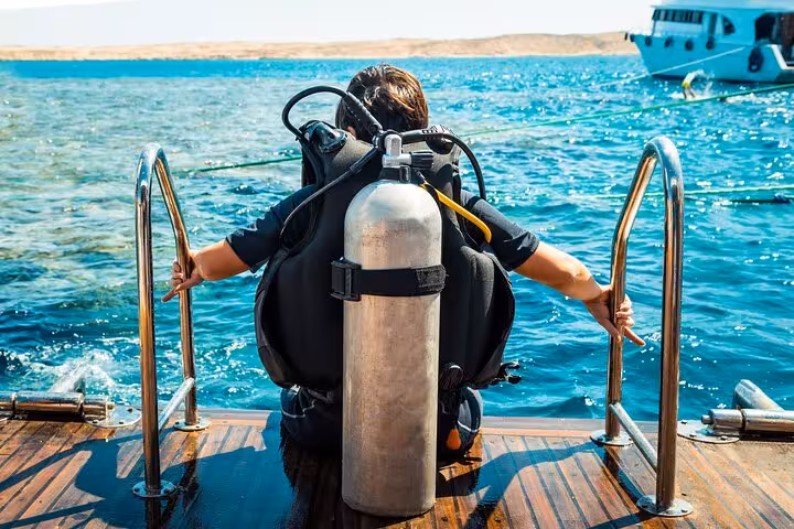 Scuba diver entering the Red Sea from a Hurghada dive boat ladder on a guided diving trip