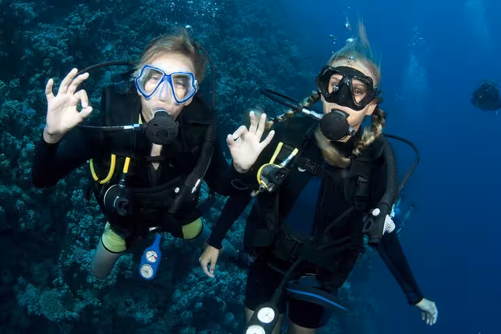 Two scuba divers giving OK sign over a Red Sea coral wall on a Hurghada diving tour for all levels