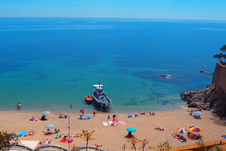 Scenic beach with a docked boat and colorful umbrellas, perfect for a relaxing day or diving adventure.