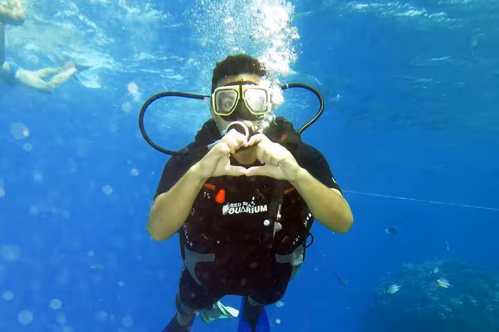 Scuba diving discovery experience diver makes heart hand sign underwater during beginner intro dive session