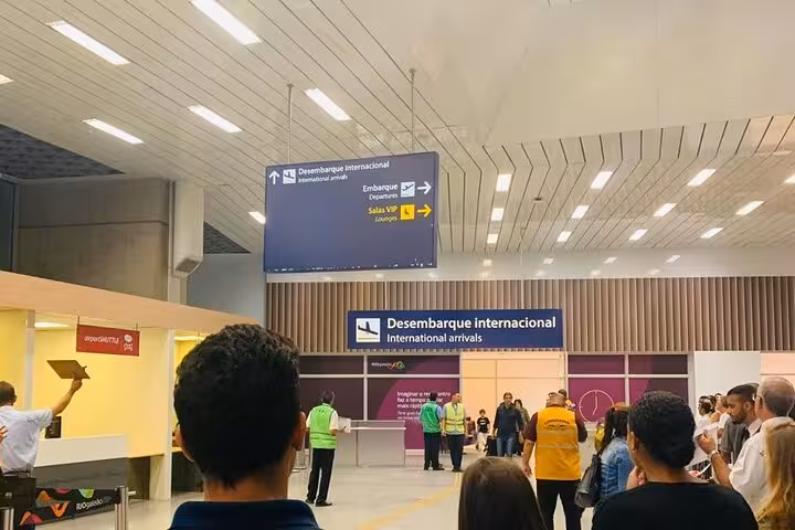 People waiting at SDU Airport's international arrivals area, highlighting private transport services to Rio de Janeiro.