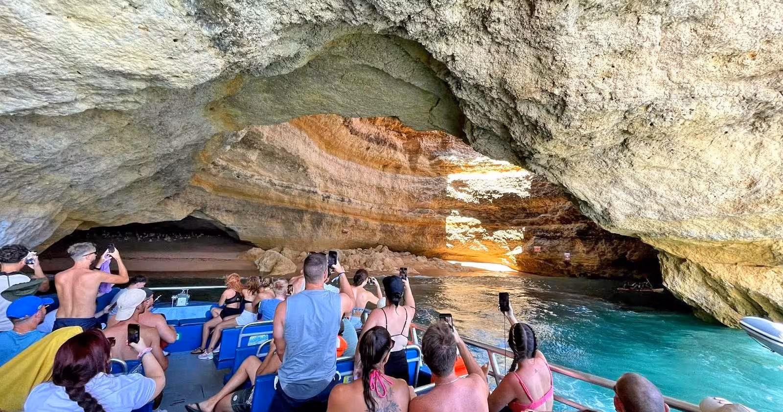 Visitors capture stunning views inside a sunlit sea cave during the Moments Special Caves & Coastline tour.