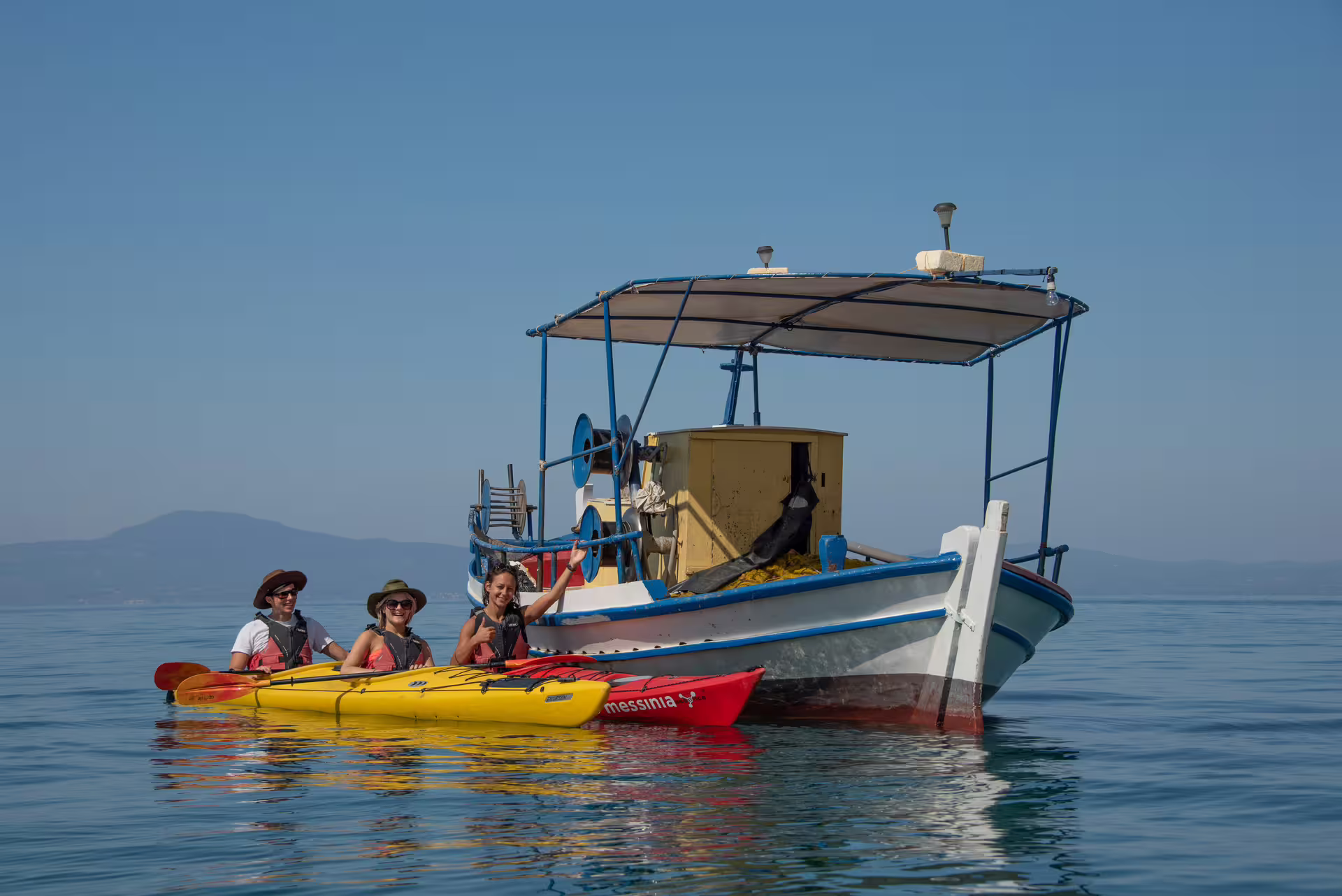 Sea kayaking in Kalamata beside a traditional fishing boat, paddling the calm Messinian Gulf in Greece