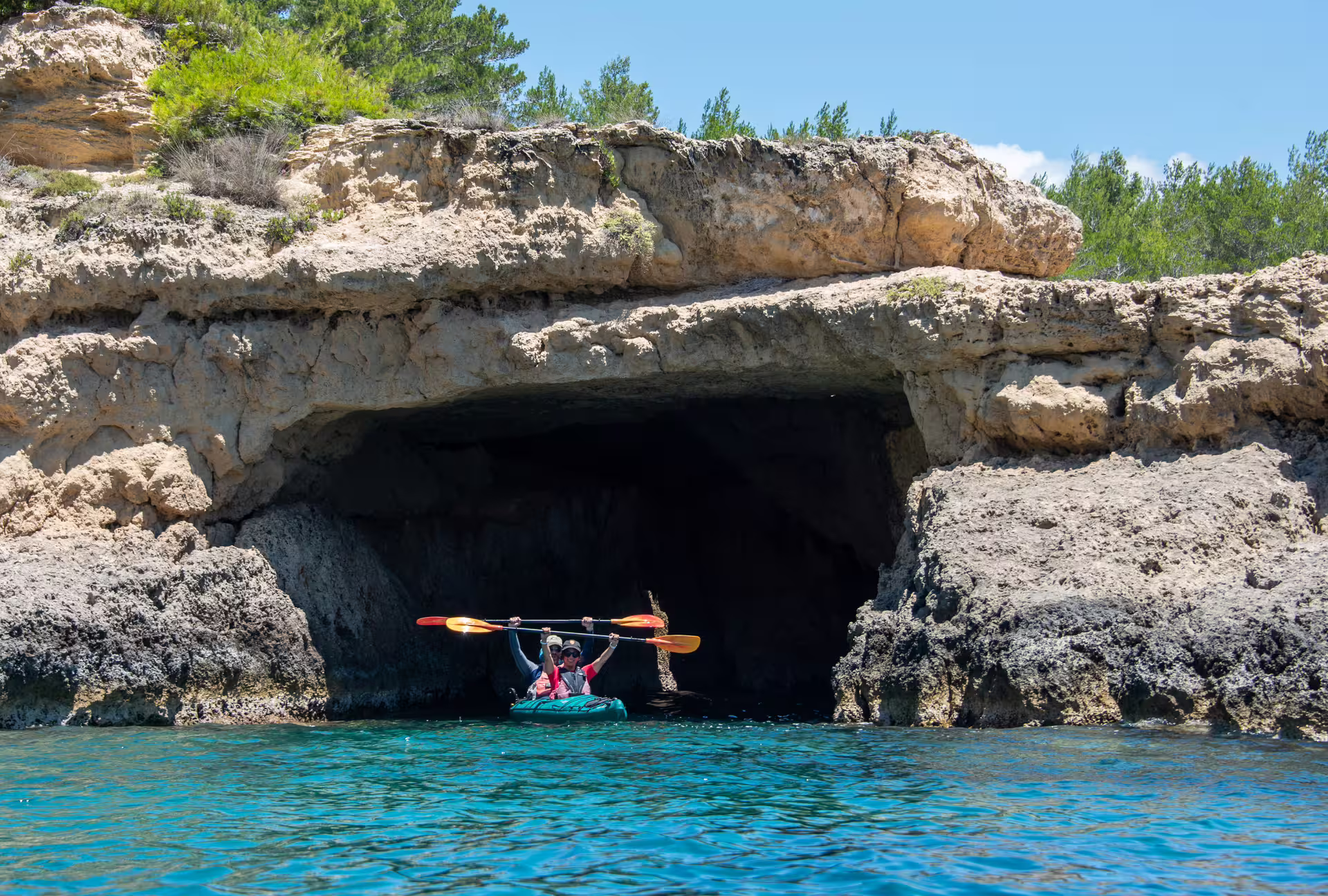 Sea kayak entering a rocky sea cave in Navarino Bay, Pylos, during guided coastal kayaking tour in Greece