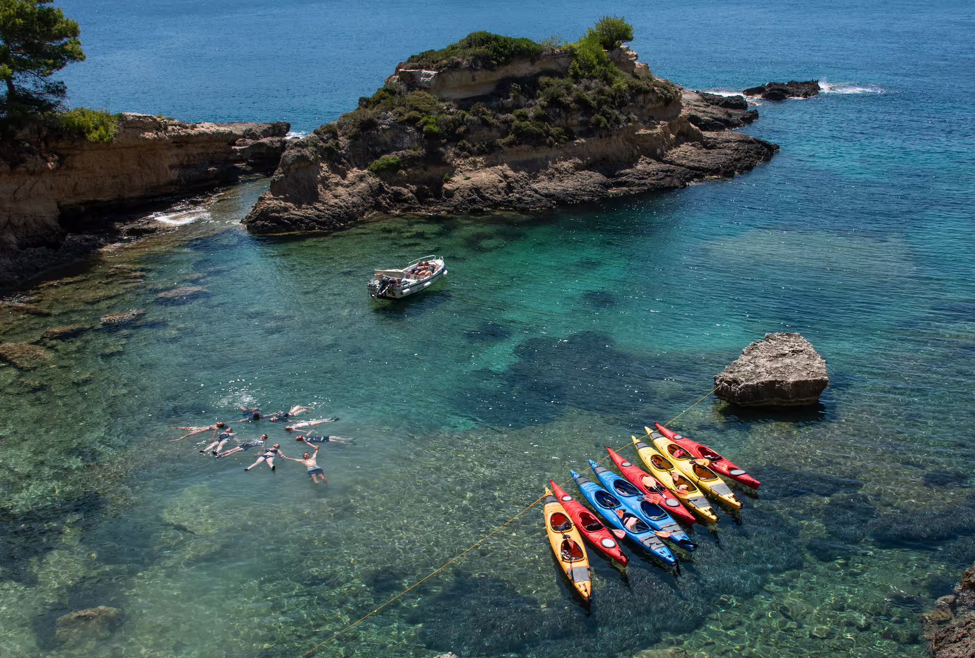 Colorful sea kayaks and swimmers in crystal-clear Navarino Bay lagoon, Pylos, on a guided kayaking tour