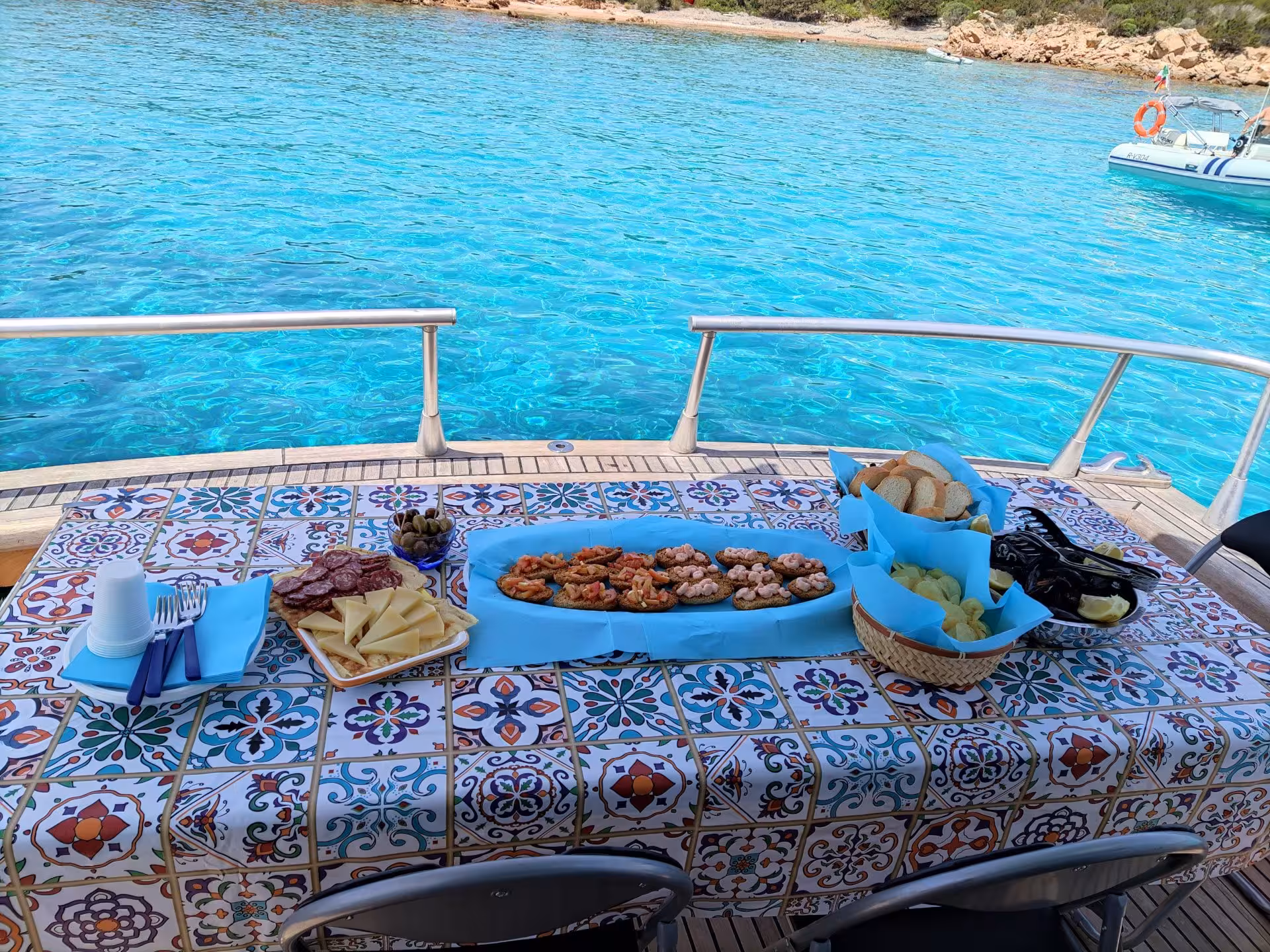 Delicious seafood and cheese platter on a boat with turquoise waters of La Maddalena Archipelago.