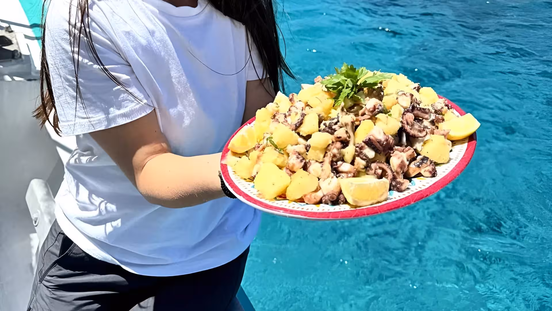 Delicious seafood platter with potatoes served on a fishing boat tour in Asinara Park's turquoise waters.