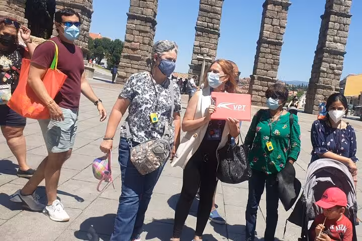 Tourists gathered near the Segovia aqueduct, enjoying a guided day trip from Madrid with optional gourmet lunch.