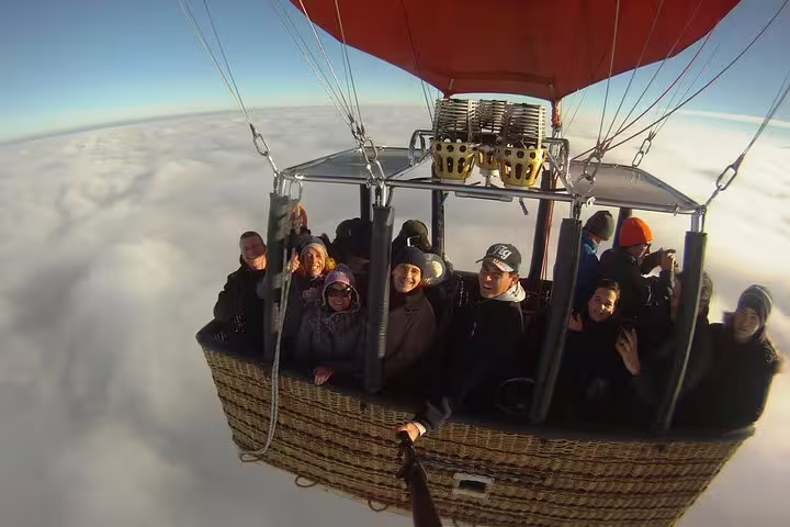 Group enjoys an exhilarating hot air balloon ride above clouds with Segovia Balloons, capturing a memorable sky-high experience.