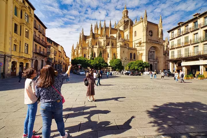 Tourists admire the stunning architecture of Segovia Cathedral, a must-see on guided tours from Madrid.