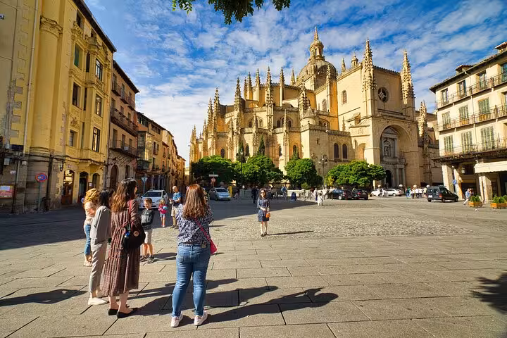 Visitors explore the majestic Segovia Cathedral under a bright blue sky during a day tour from Madrid.