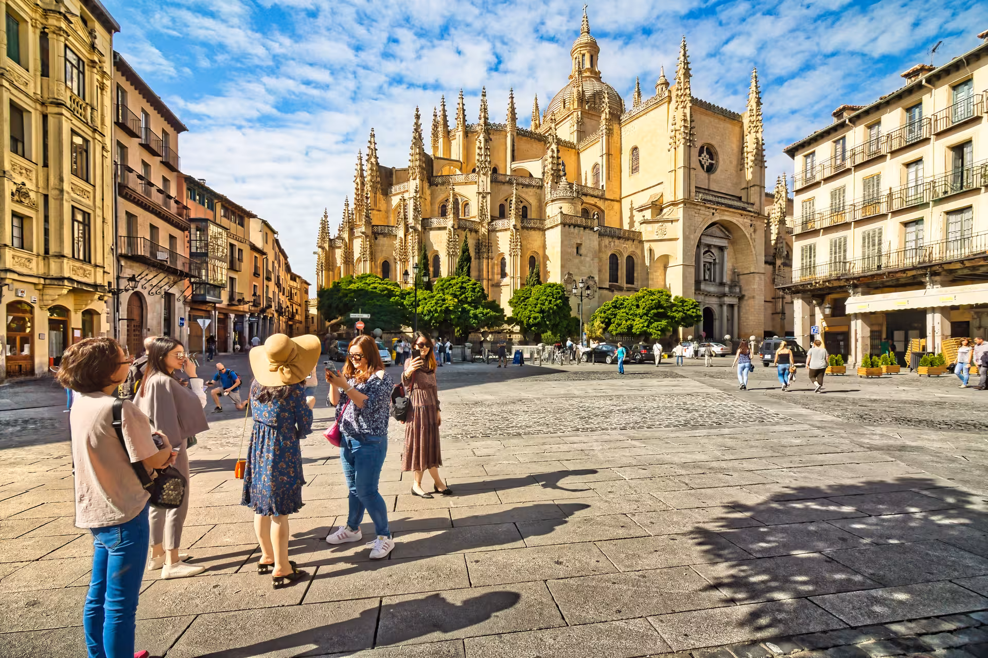 Visitors gather and take photos in front of the majestic Segovia Cathedral on a sunny day tour from Madrid.
