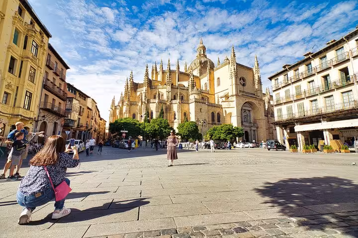 Visitors capture memories in front of Segovia Cathedral, highlighting the cultural allure of Spanish heritage tours.