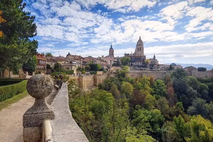 Scenic view of Segovia's historic skyline featuring the cathedral, lush greenery, and picturesque architecture.