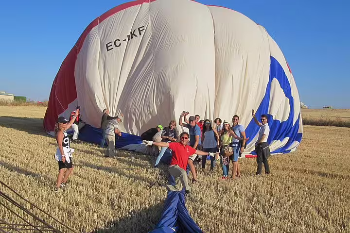 Tourists celebrating post-flight with a deflated hot air balloon in the picturesque fields of Segovia.