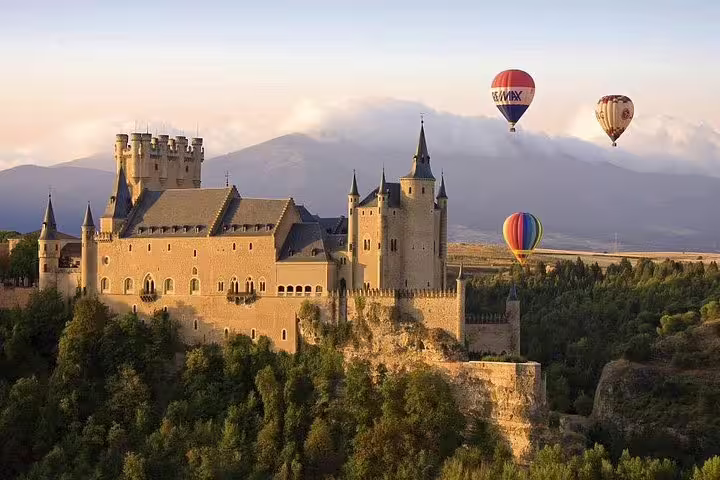 Hot air balloons soar over Segovia's Alcázar at sunrise, offering breathtaking aerial views of Spain's historic landmark.