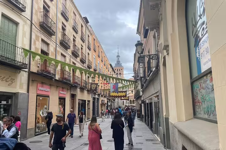 Pedestrian street in Segovia old town with festive banners, ideal stop on private minivan tour from Madrid