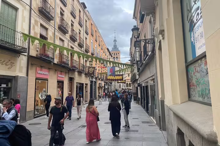 Lively Segovia old town street with shops and pedestrians, explored on a private Segovia tour by minivan