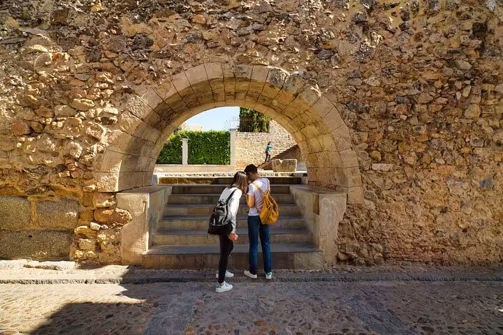 Visitors explore ancient stone archways in Segovia on a day trip from Madrid with optional gourmet lunch.
