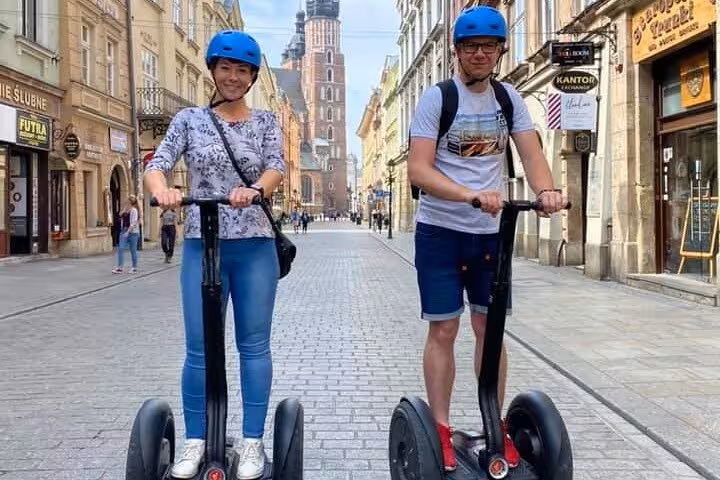 Two tourists enjoying a 120 min Old Town Segway Tour in Krakow, showcasing beautiful historic architecture.