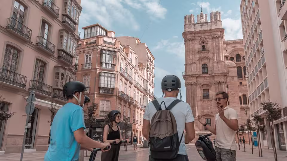 Segway tour group explores Malaga's historical architecture, stopping at the impressive Malaga Cathedral for insights.