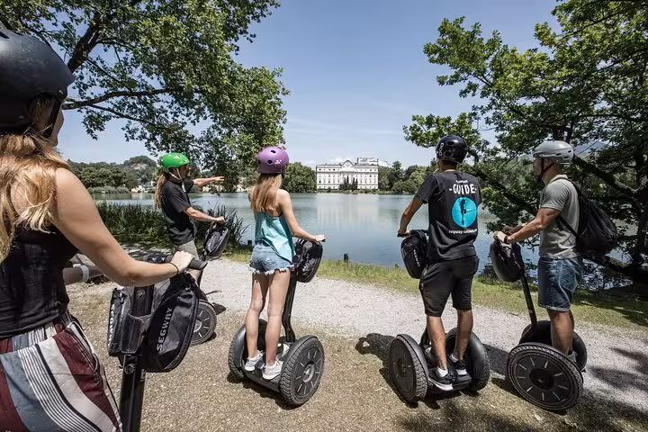 Group on Segways admiring a lakeside castle in Salzburg on the City Mountain and Castle Tour.