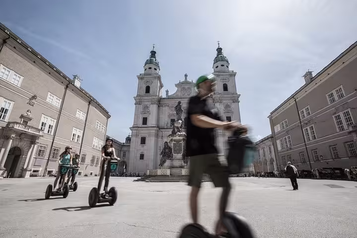 Tourists enjoy a Segway ride in Salzburg's historic Residenzplatz, with the stunning Salzburg Cathedral in the background.