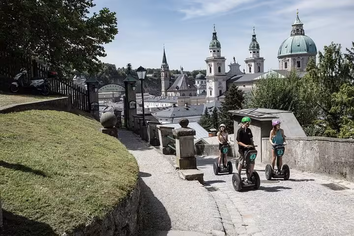 Group riding Segways through historic Salzburg with stunning cathedral backdrop.