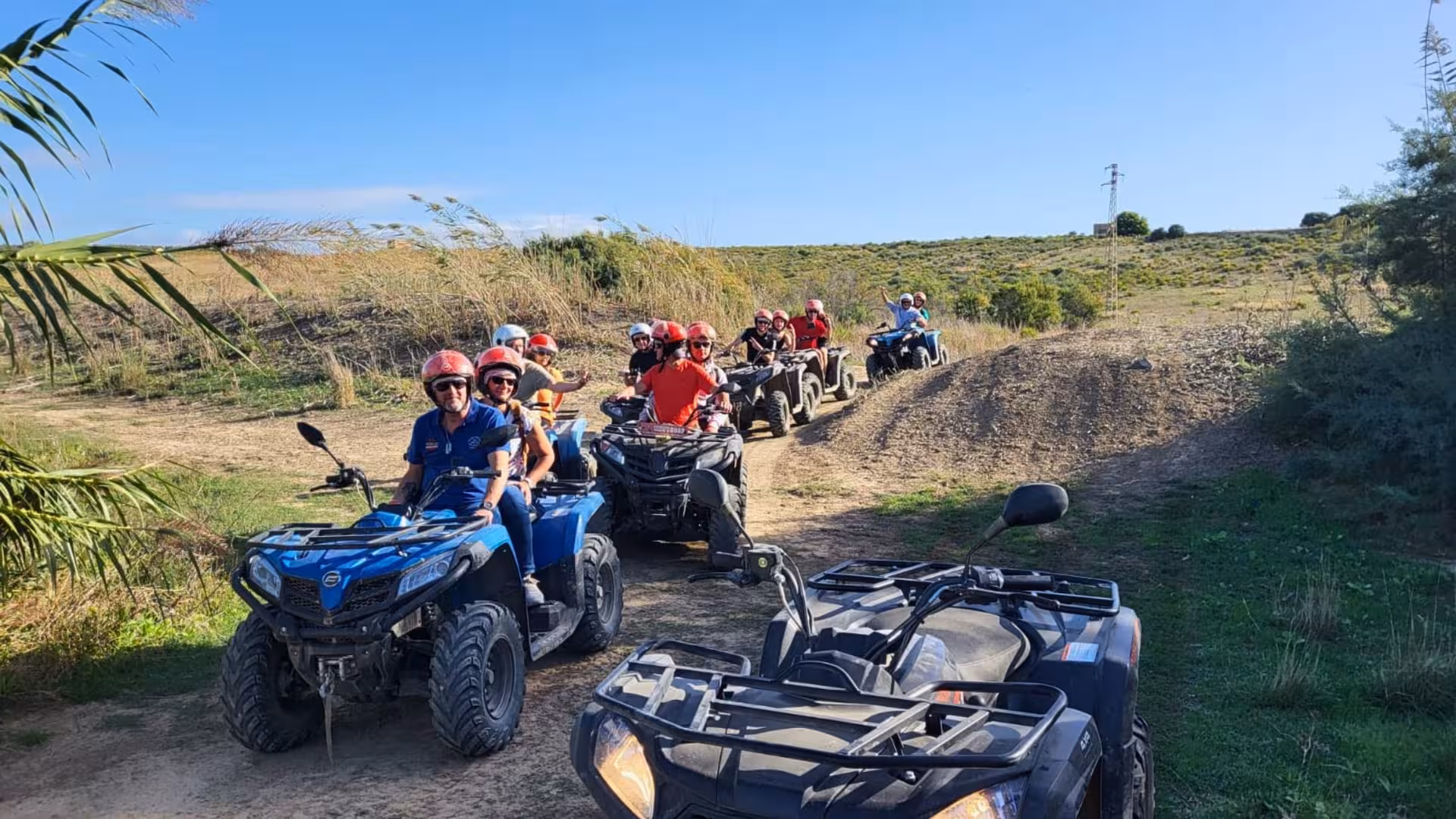Excited tourists on ATVs navigating the scenic trails of Triscina dunes in Selinunte under a clear blue sky.